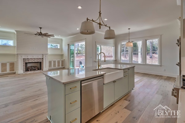 Luxury Kitchen Island With Farmhouse Sink And Stainless Steel Dishwasher And Living Space With Shiplap Fireplace Custom Built Ins And Brick Fireplace Surround