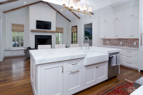 Luxury Kitchen With Brick Backsplash White Cabinets Hardwood Floors And Cathedral Ceiling With Exposed Wood Beams