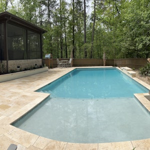 Custom in-ground concrete pool and natural stone paver patio with outdoor kitchen in South Carolina.