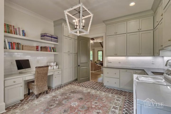Luxurious Laundry Room With Brick Floor And Green Cabinets And Home Office Space Combo