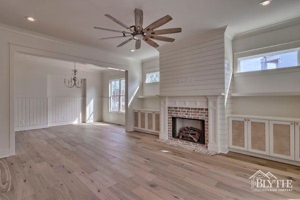 Living Space With Rustic Hardwood Floors Shiplap Fireplace Brick Fireplace Surround Custom Cabinets Floating Shelves And Rectangular Windows With View Of Dining Room