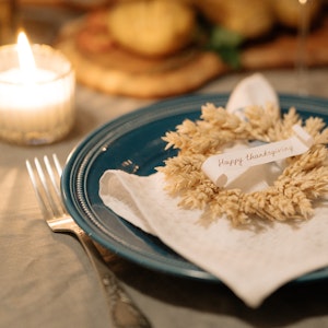 Thanksgiving-place-setting-with-blue-plate-white-cloth-napkin-wreath-and-candle