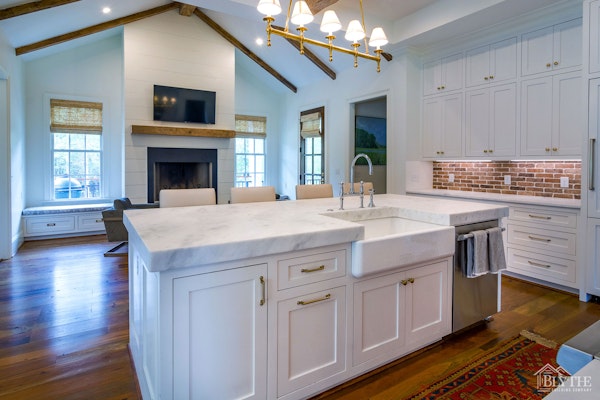 White kitchen with marble countertop on island and real brick tile backsplash