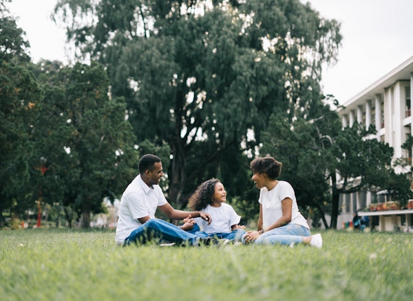 Family-sitting-on-grass-in-park-smiling