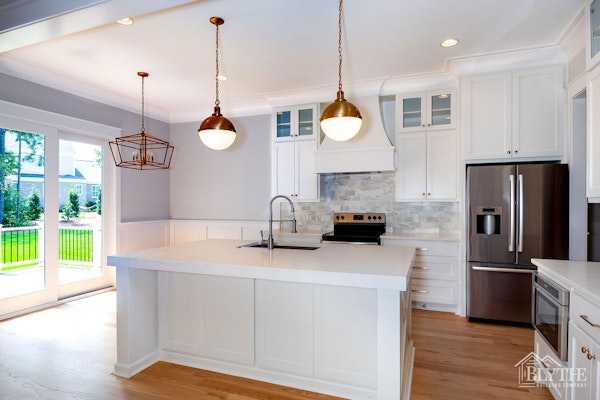 Kitchen with white shaker cabinets, bronze pendant lights, and marble tile backsplash|Blythe Building Company