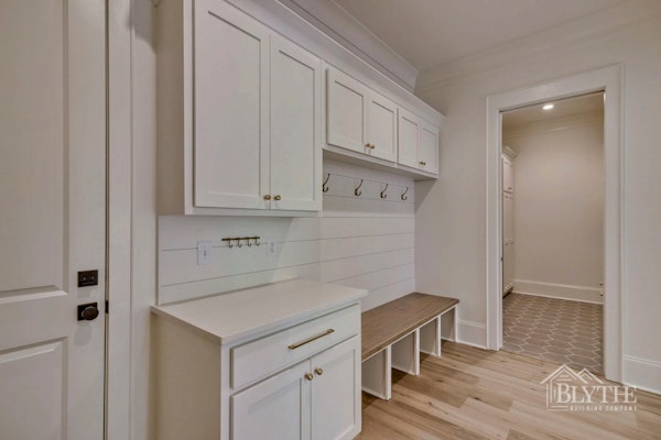 Mudroom Area With Custom Cabinets Bench And Cubbies With Shiplap Beside Laundry Room With Hexagon Tile 