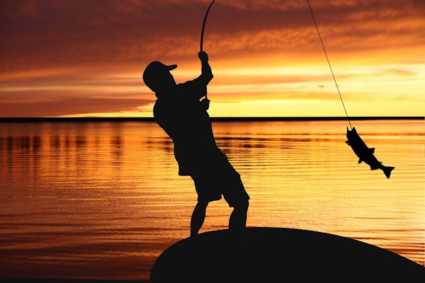 A man fishing at sunrise on a beautiful lake.