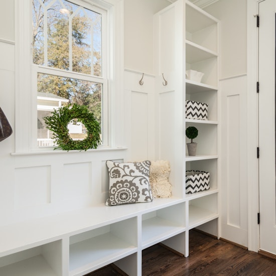 White mudroom with built-in cabinets, cubbies, and hardwood floors
