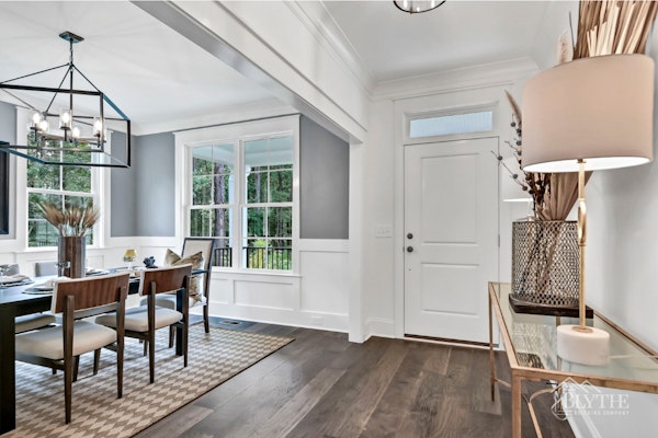 Front Foyer With Transom Over Door And View Of Gray Dining Room With Wainscoting And Extra Large Chandelier