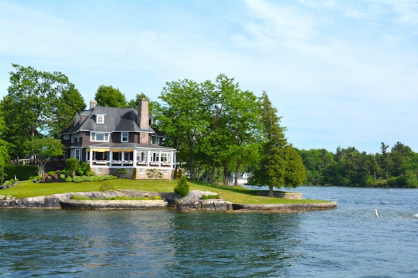 A 3-story luxury home on a lake with a stone retaining wall.