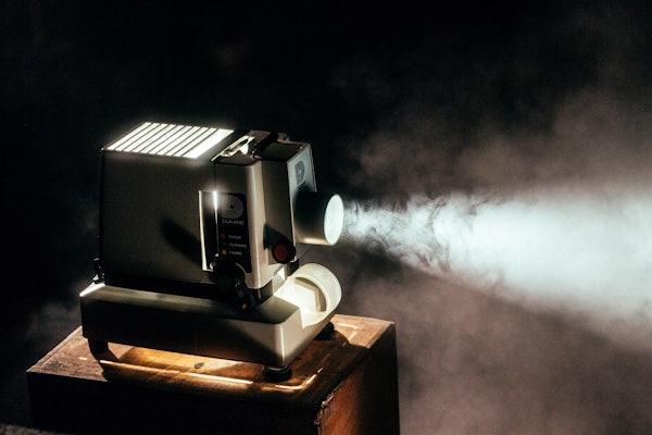 Portable home movie projector in a dark room on a wooden table
