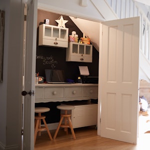 Entryway office in a closet with white doors and white built-in desk