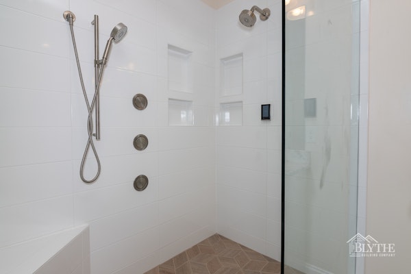 Large custom shower with dual shower heads and 3 body jets. White subway tiled shower and corner custom shower bench.