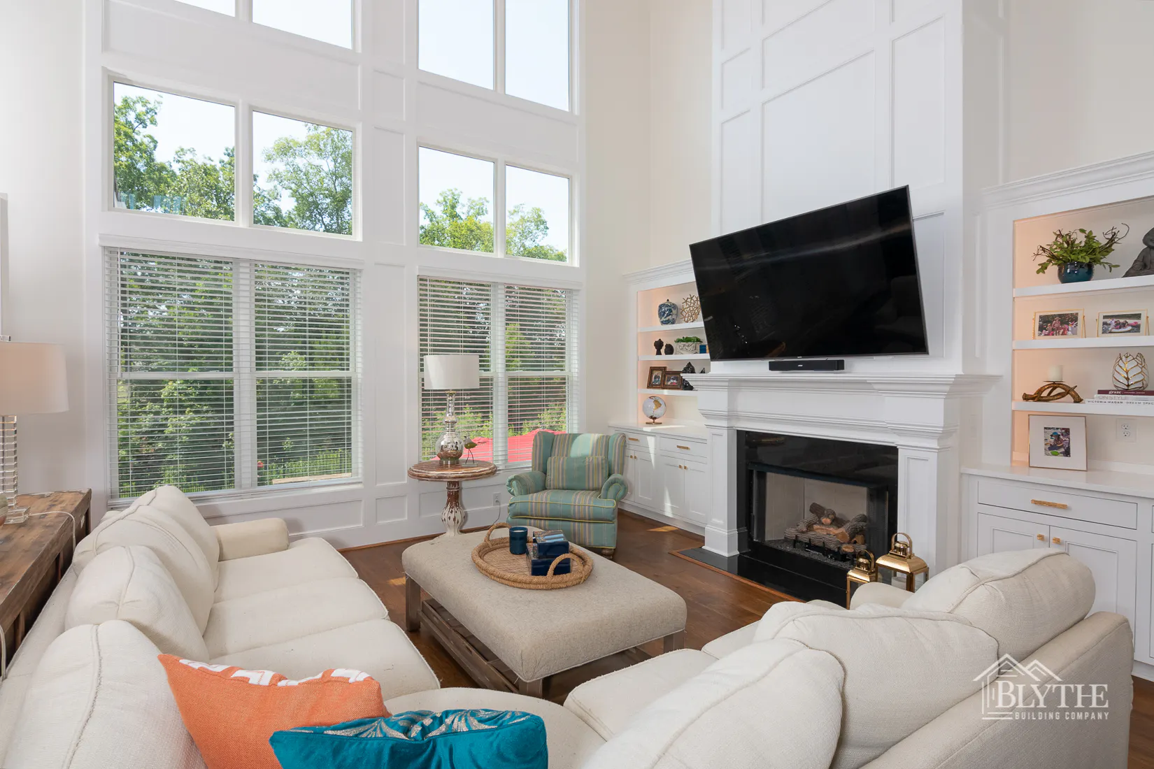 two-story ceiling living room with molding on the wall over the fireplace