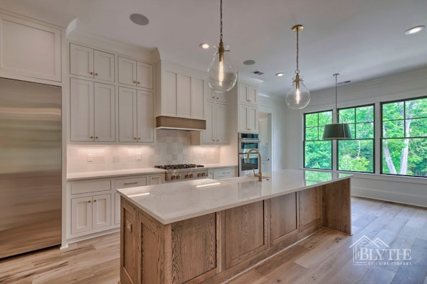 French Country Modern Kitchen With Custom Cabinets And Large Woodgrain Kitchen Island With Farmhouse Sink And Custom Pendant Lighting