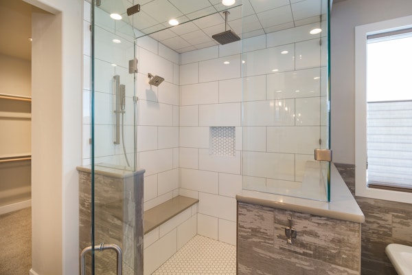 Steam shower - custom built - with partial wall and tall glass enclosure, rain shower head, and custom shower bench.