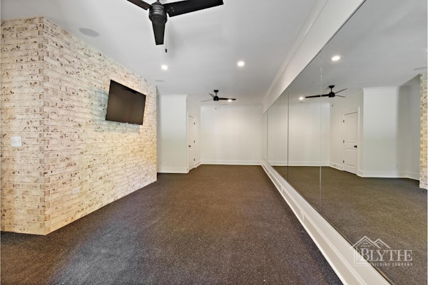 A Custom Home Gym In The Basement With A Mirror Wall And A Limewashed Brick Wall 